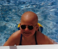 Amy in pool, with a big beautiful smile and a completely bald head