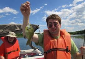 Boy smiling and holding up fish on fishing line