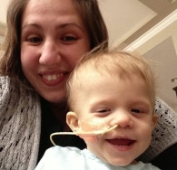 Mom smiling with young child with feeding tube in nose
