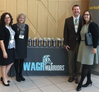Image of conference attendees, standing in front of WAGR Warriors sign 